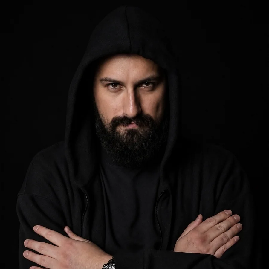 Dano Čistý v čiernej mikine s kapucňou na čiernom pozadí